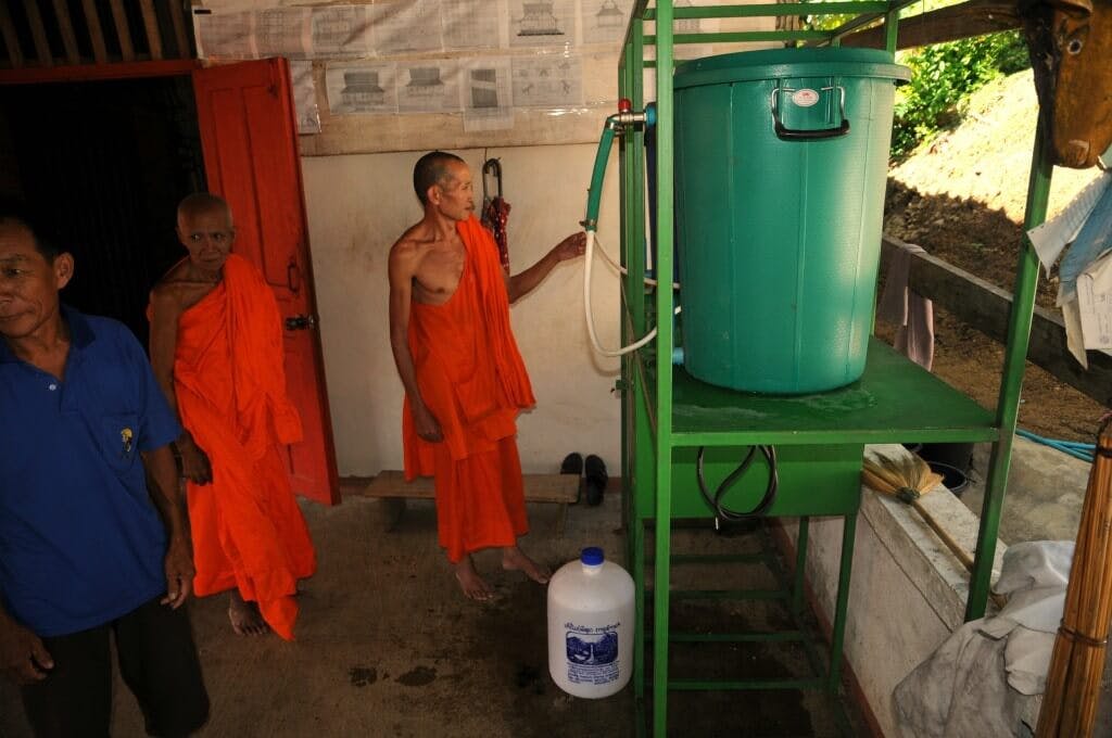 An elderly monk inspects the newly installed water purification system.