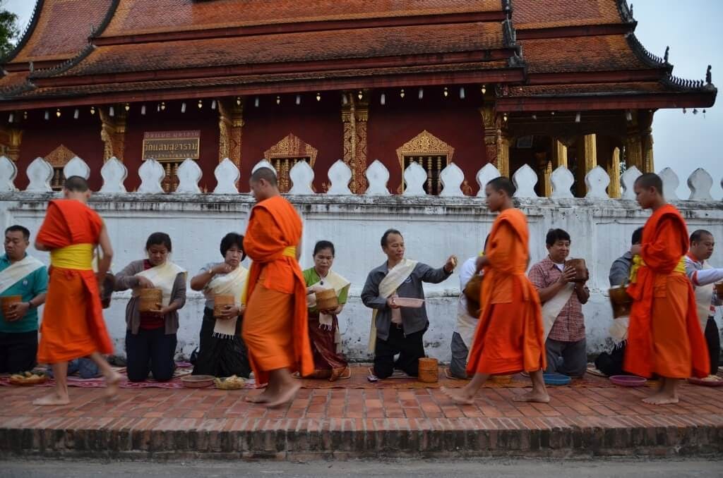 Monks and novices walking through the streets in the early morning accepting offerings of food from the villagers.